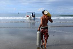 A snorkel instructor helps carry diving tanks to the boat for a snorkel diving tour at Cano Island on August 19,, 2013.